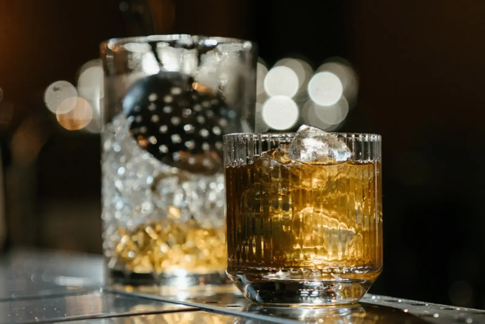 Două pahare de whisky ciocnite, într-o atmosferă de cinema
